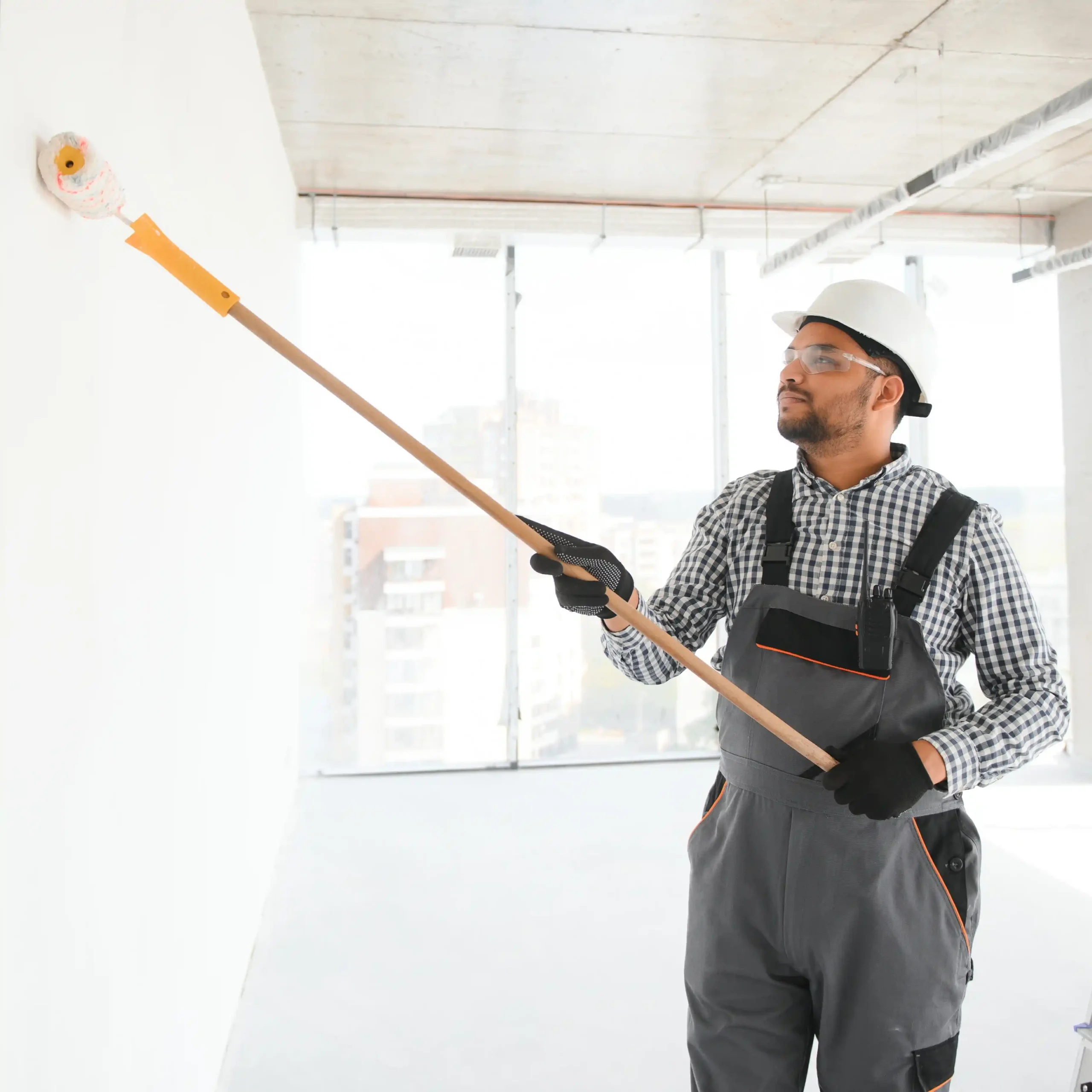 Professional painter applying white paint to interior wall with roller